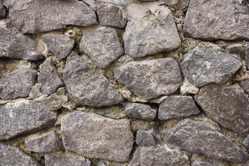 Fragment of an old stone wall made of gray rough stones. Textured background. Close up