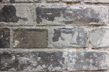Fragment of an old wall made of dark gray stone blocks. Close up. Background. Texture.