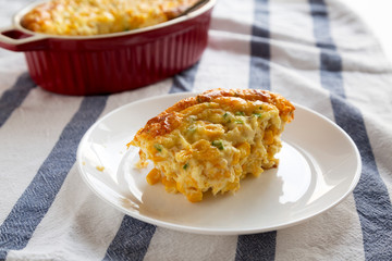 Tasty Homemade Cheddar Corn Pudding Casserole on a white plate, low angle view. Close-up.