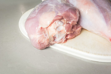 Thawed raw turkey legs on white cutting board for cooking.