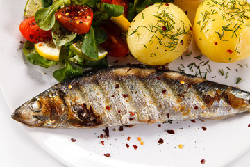 Fish dish - grilled herring with vegetables on white background