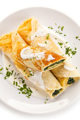Crepes with spinach and feta cheese on white background
