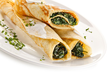 Crepes with spinach and feta cheese on white background