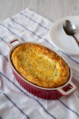 Homemade Cheddar Corn Pudding Casserole on a white wooden background, low angle view.