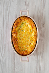 Homemade Cheddar Corn Pudding Casserole on a white wooden background, top view. Flat lay, overhead, from above.