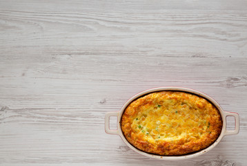 Homemade Cheddar Corn Pudding Casserole on a white wooden background, top view. Flat lay, top view, from above. Space for text.