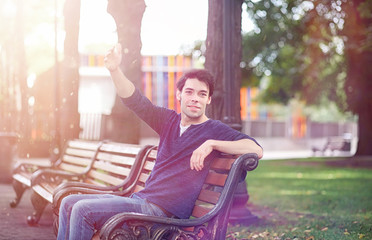 A young man walks in the park at lunch time. A man is on a walk in the city. A student in the park.