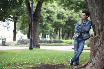 Fototapeta premium A young man walks in the park at lunch time. A man is on a walk in the city. A student in the park.