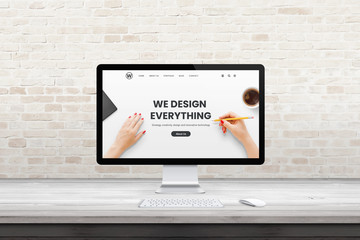 Modern computer display with web design agency page on office, studio desk. Flat design concept. Modern flat design interior with brick wall in background