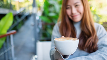 Closeup image of a beautiful asian woman holding a cup of hot coffee
