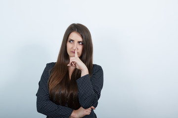 Charming caucasian woman over isolated gray background wearing casual black dress with white polka dot, keeping finger on nose, looking aside. People lifestyle concepte.