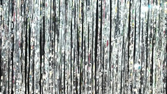 Silver rain from tinsel. Dynamic background in shining lights and sparkling particles. Beautiful silver background with shiny silver glitter sparkles. Festive mood. Christmas or holiday theme
