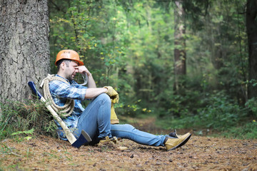 Male lumberjack in the forest. A professional woodcutter inspects trees for felling.