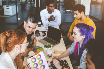 Group of multi ethnic executives discussing during a meeting. Business man and woman sitting around table at office and smiling. A team of young creative designers