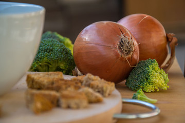 Close-up of healthy vegetarian food, vegetables - green broccoli, bread and onions in the kitchen placed on wooden table