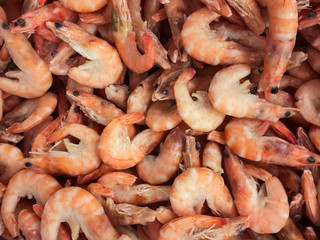 Close-up of a pile of frozen orange shrimps. Natural seafood background
