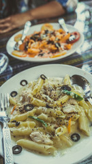 Pasta with white sauce with seafood, on a white plate with Cutlery