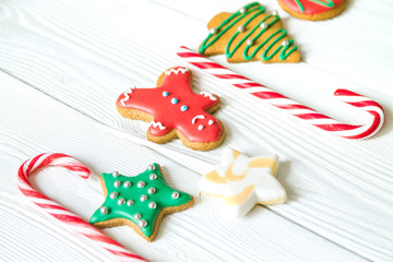 traditional Christmas sweets on white wooden background. Candy cane, round snowflake and ginger man, star lollipop. Top view. Christmas concept