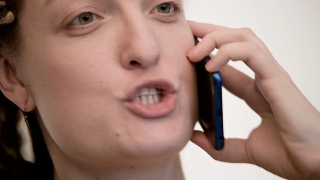 Ethnic woman talking on phone, angry. White background. Big closeup.