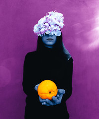 Female hand holding orange. Portrait Of Young Girl standing on color  background