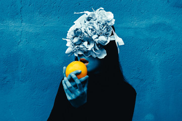 Female hand holding orange. Portrait Of Young Girl standing on color  background