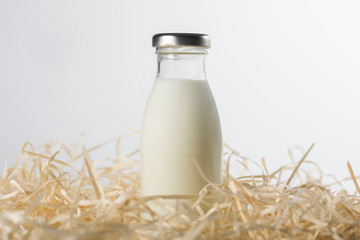 Bottle of fresh milk in the hay on a white background. Healthy food.