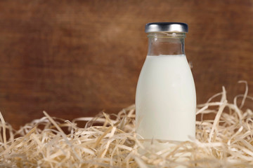 Bottle of fresh milk in the hay on a wooden background. Healthy food. Milk product.