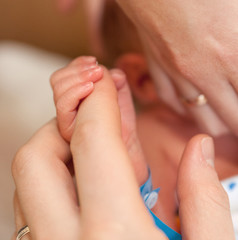 The baby clings to his mother's finger