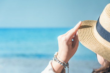 Woman in a straw on a beach with sea view.