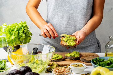Woman cooking avocado sandwiches in a kitchen. Healthy food concept.