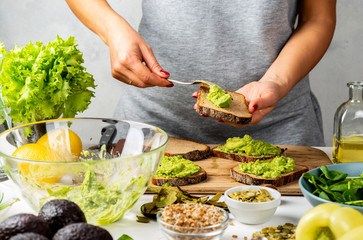 Young woman cooking avocado sandwiches in a cuisine.