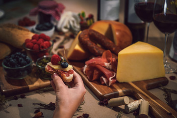 Serrano ham and cheese tapa and in the background a rustic table of gourmet ingredients