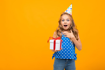 Nice little girl with a birthday party holds a present isolated on white background