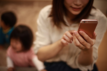 スマートフォンの操作に夢中になる母親