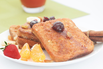 A plate of french toast with bananas, oranges,strawberries and jam. Sweet breakfast with french toast and fruit.