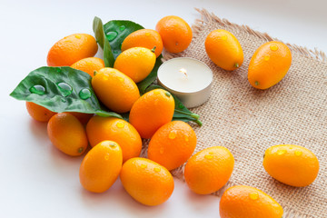 Still life of kumquats and candles on sackcloth. Relaxing background. Background for spa design.