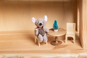 Gray mouse toy as a symbol of the new year 2020. A miniature Christmas tree on a table in a doll house