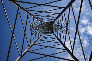 Wide angle view of a electric grid tower with blue sky and clouds