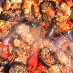 Homemade sausage and eggplant sauce cooked in a pan, close-up, top view