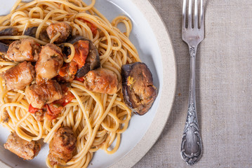 Spaghetti with homemade sausages and eggplant in a plate close-up, top view - traditional Italian pasta