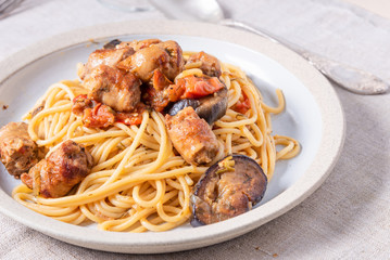 Spaghetti with homemade sausages and eggplant in a plate close-up - traditional Italian rural lunch