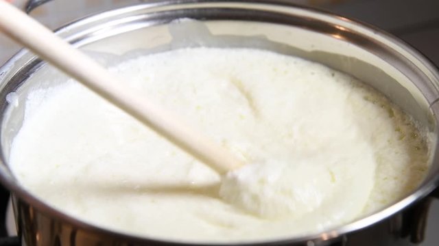 Close-up of cooking homemade curd or cottage cheese from homemade kefir. Kefir boils in a pan, sour milk curdling and turning into cottage cheese. Concept of fermented food