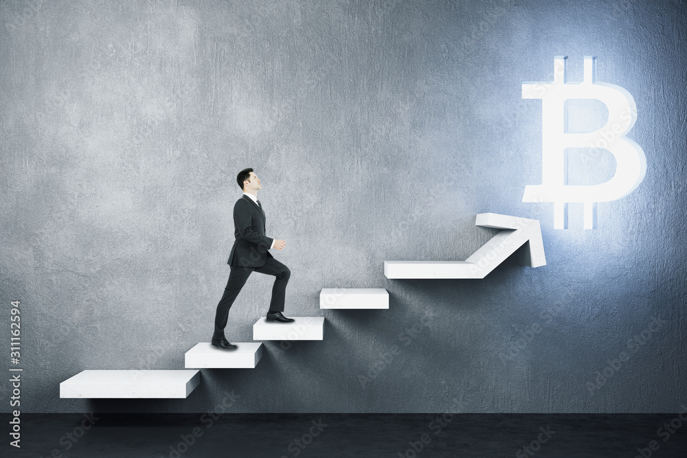 Wall mural Young businessman climbs on stairs to glowing  bitcoin sign.