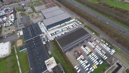 Aerial overview of trucks at industrial parking lot next highway