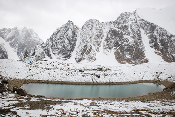 Blue lake high in mountains. Against background of snowy peaks. Beautiful winter photo