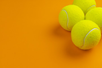Four tennis balls on an orange background