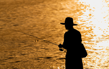 Silhouette of fishing man in sunset time.