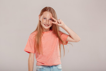 Inclusive Beauty. Girl with freckles standing isolated on grey posing showing salute gesture cool