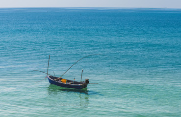 Naklejka na ściany i meble Small wooden fishing boat in the blue sea.
