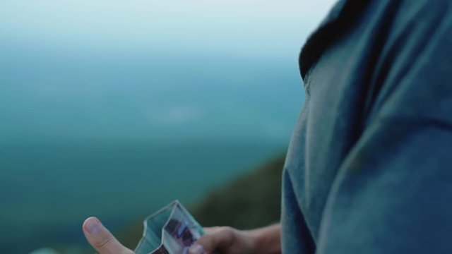 Close up hands opening an old tin box on a windy, overcast day on a mountin